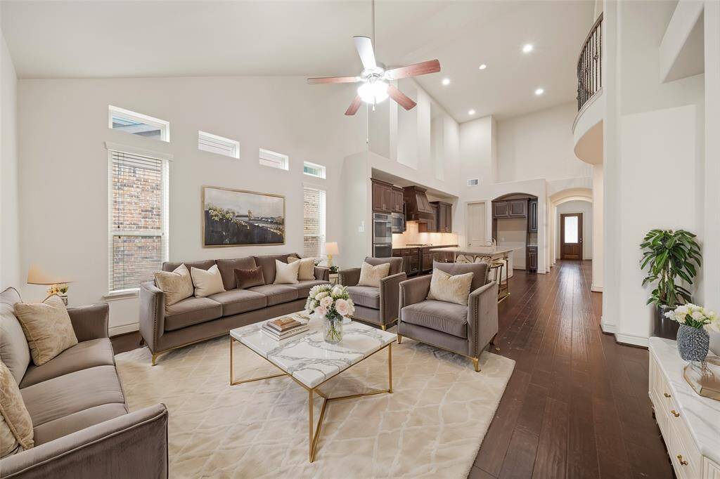 Living room with wood flooring, high ceilings & a ceiling fan.