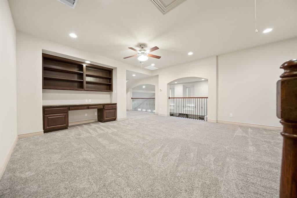 Spacious game room with a ceiling fan, carpet, a built-in desk/shelving and recessed lighting!