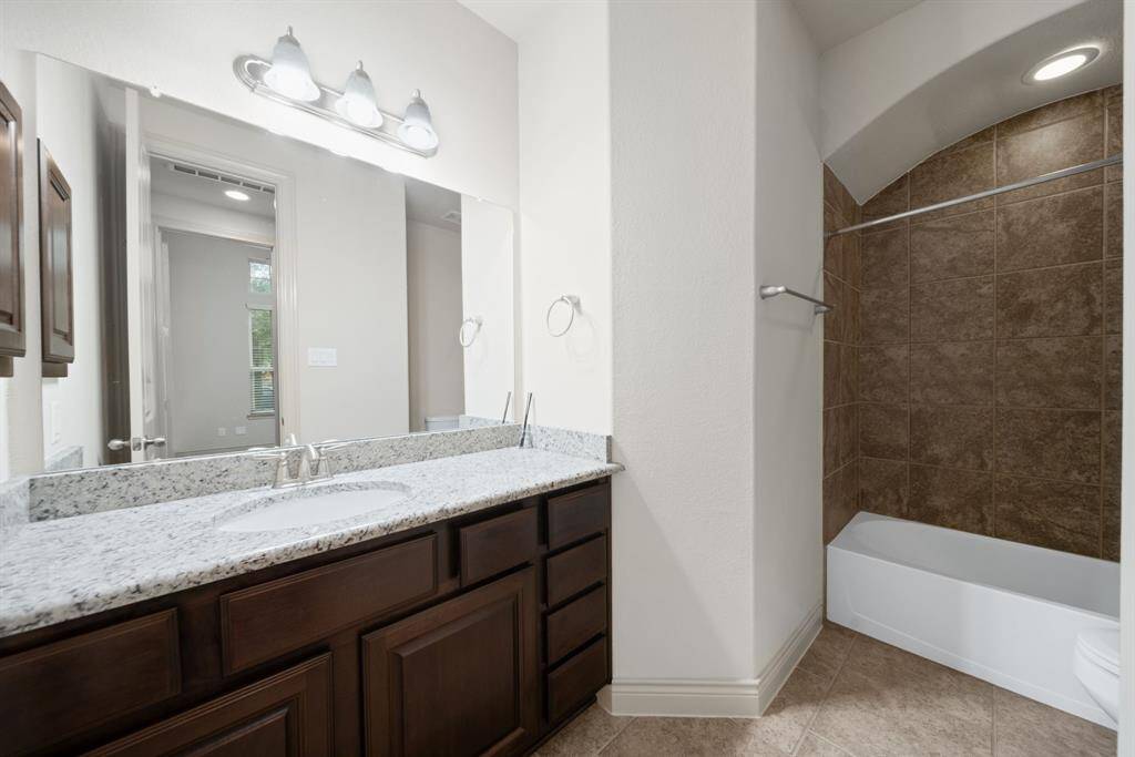 Full bathroom with granite countertops, tile flooring and a shower/tub combo downstairs.