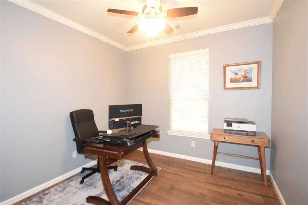 French doors open to the study accented by hardwood type flooring, crown molding and a ceiling fan with light fixture.