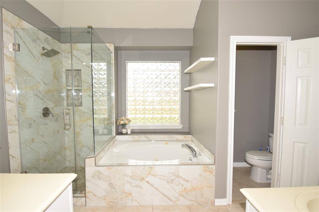 Primary bath offering a large jetted tub, separate shower, two sink areas and two walk-in closets.