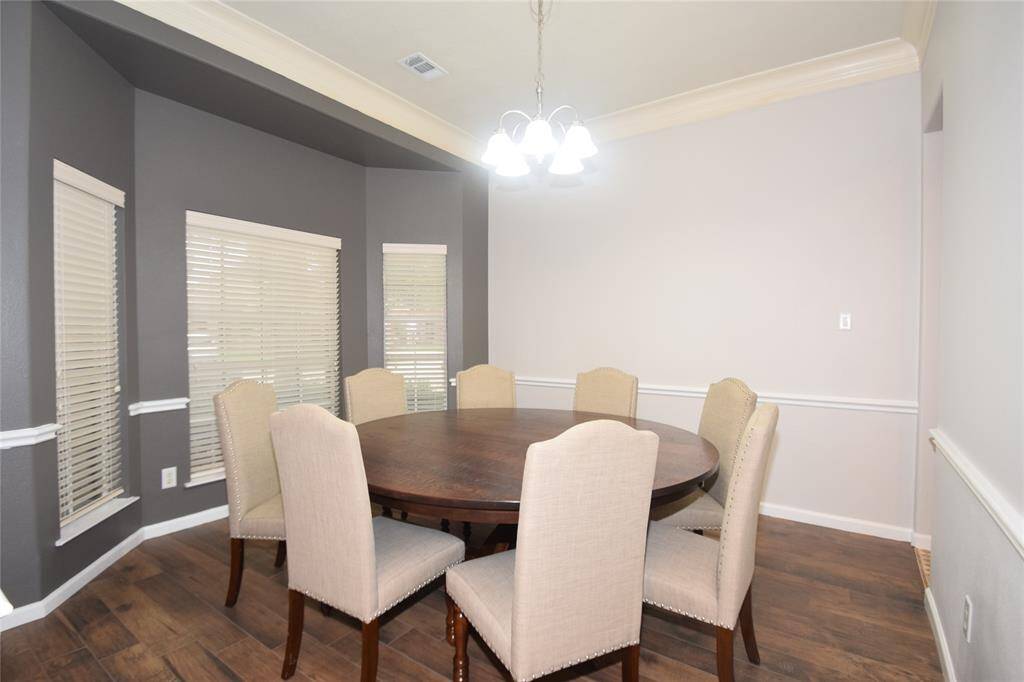 Dining room dazzled by hardwood type flooring, double crown molding, chair rails, bay window and access to the kitchen.