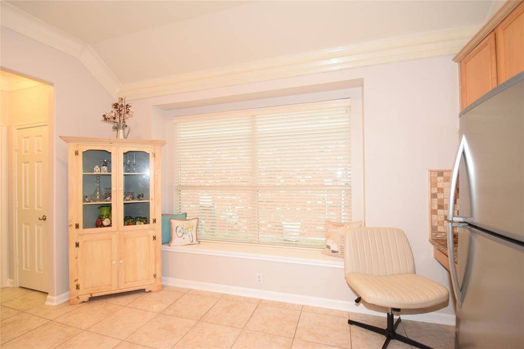 Breakfast room highlighted by tile floors, built-in desk, raised ceilings, double crown molding, box window and opens to the kitchen.