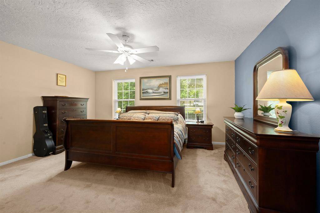 Primary bedroom overlooks the beautiful front landscape and tall trees.
