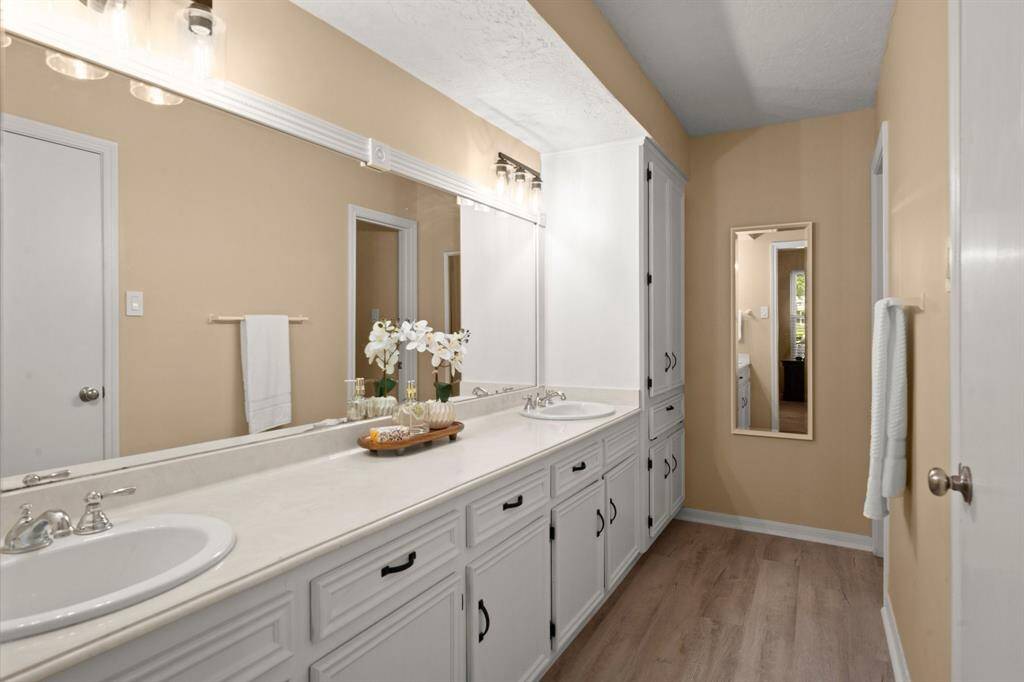 Recent flooring, updated light fixtures, and a framed mirror—along with double sinks—make getting ready in the morning a breeze.