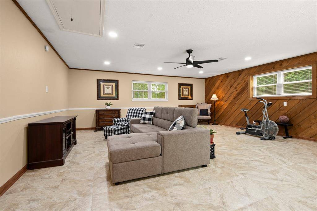 LOVE the huge, downstairs, sun-filled game room! Country chic accent wall, large windows, updated ceiling fan, recess lighting and low-maintenance flooring are perfection. Think of all the ways you can use this room. There is an exterior door along the back wall (unseen).
