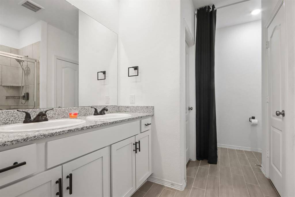The primary bathroom boasts granite countertops, tile floors, a large mirror, double sinks, and walk-in closets.