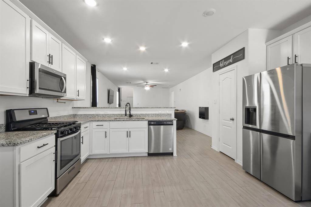This fully equipped kitchen features an abundance of cabinetry and hardware, TONS of counter space, granite countertops, recessed lighting, stainless-steel appliances, and a walk-in pantry