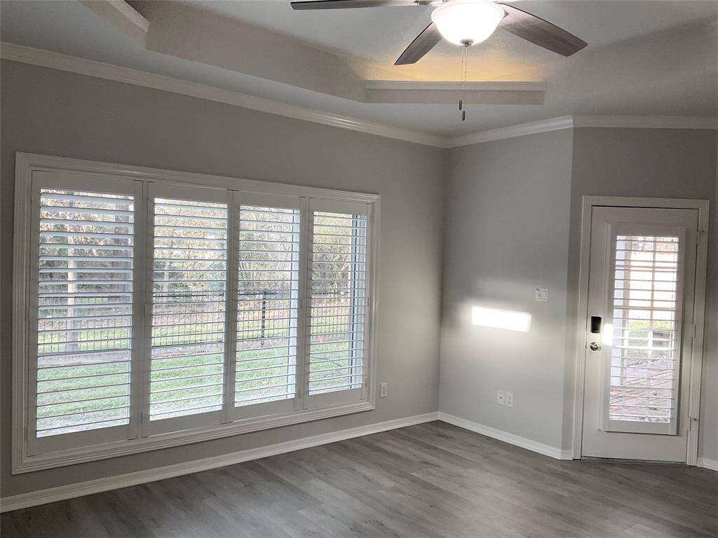 The Primary bedroom is bright with large windows a door to the back patio and recessed lighting.  It has light gray walls, new flooring, a ceiling fan, offering a cozy and airy ambiance. Perfect for enjoying natural light and garden views.  Step outside and enjoy your coffee.