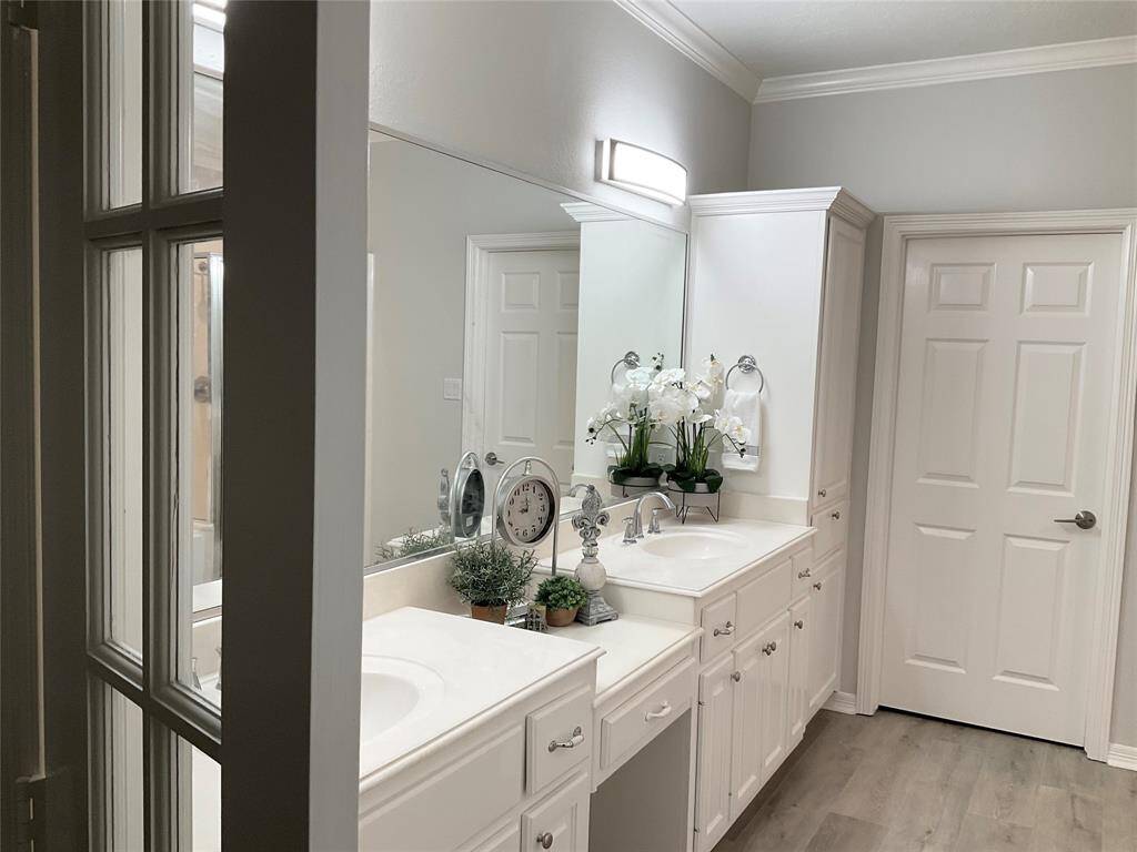 This bathroom features a modern design with dual sinks, ample cabinet space, and a large mirror. The light color palette and contemporary fixtures create a bright and inviting atmosphere.