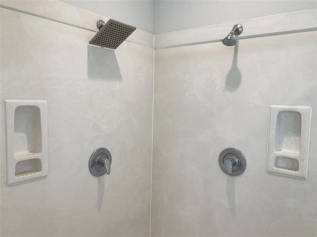 Dual shower heads, sleek chrome fixtures, and built-in soap niches as well as a bench seat for convenience.