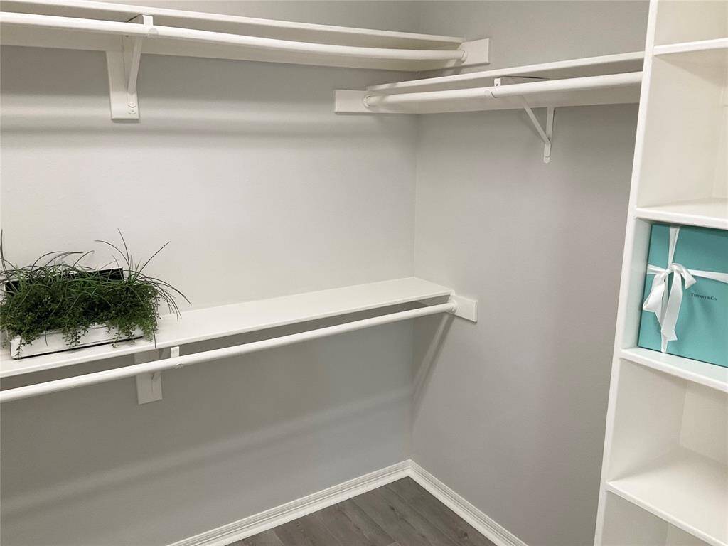 Other side of the spacious walk-in closet with white shelving and hanging rods, featuring a clean, modern design.  It is bright and will be easy to organize efficiently,