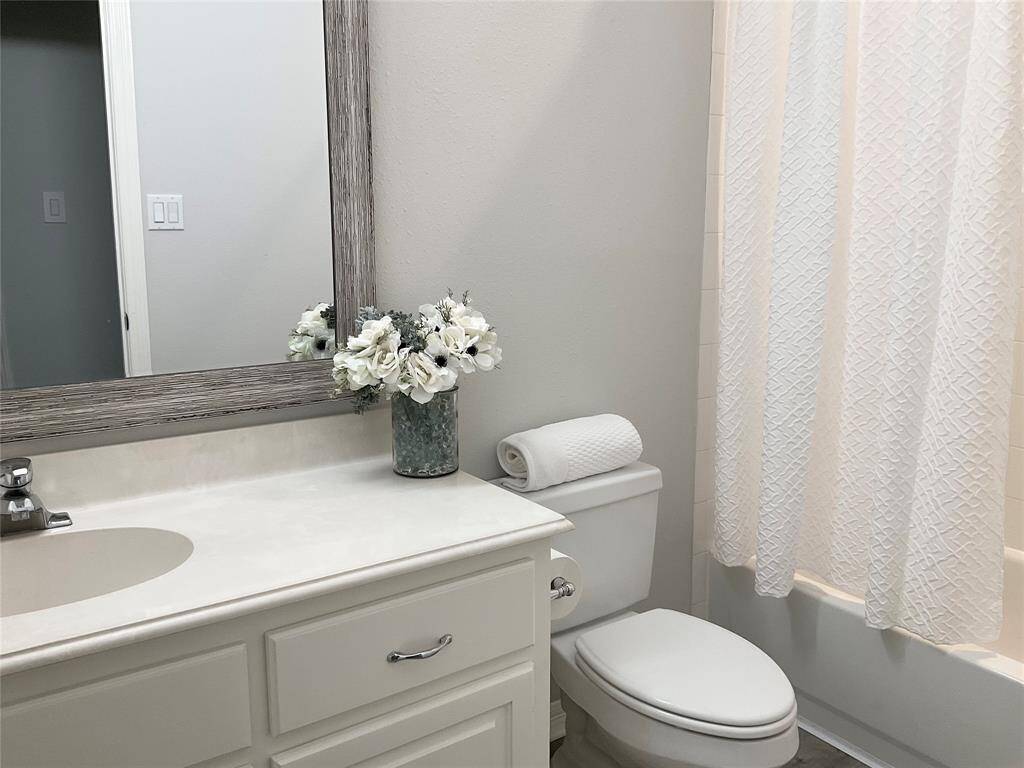This bathroom features a clean, modern design with a light color palette. It includes a vanity with a large framed mirror, New light fixtures, and a tub shower combination.  This 2nd bathroom also serves as your guest bath located off the family room and home office.