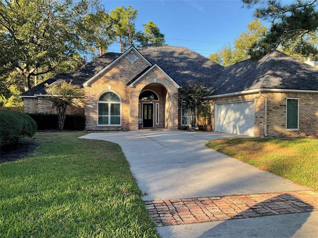 This charming home features a brick exterior with a welcoming arched entryway. It boasts a well-maintained front yard with mature trees and a spacious driveway leading to a two-car, side load garage. The design includes large windows that enhance natural light inside.