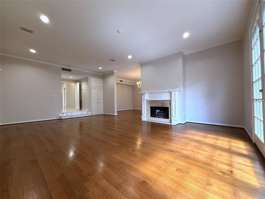 Alternate view of the living room offering a fireplace and recessed lighting.
