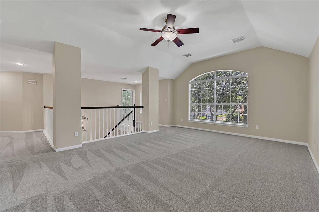 Head on upstairs to this spacious game room featuring brand new carpet, fresh paint, an elevated gambrel ceiling, and a beautiful arched window that brings in abundant natural light—perfect for relaxing or entertaining.