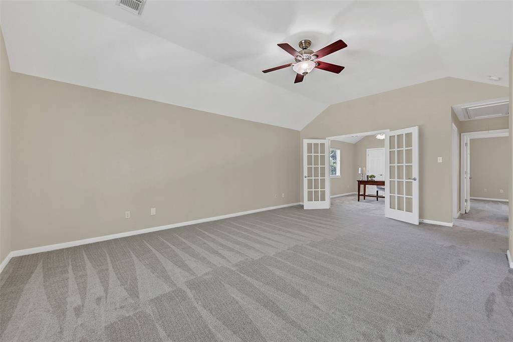 An alternate view of the spacious game room highlights the ample space as well as the French doors that open to a versatile bonus space—perfect for a home office, playroom, or potential 5th bedroom.
