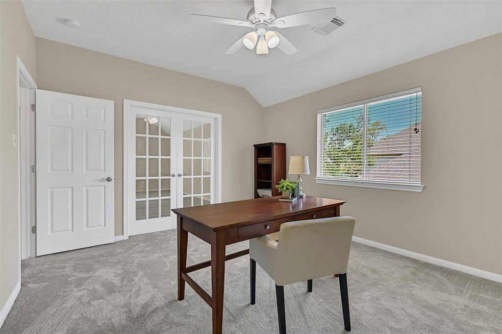 This flexible bonus room features French doors, brand new plush carpet, fresh neutral paint, a lighted ceiling fan, a walk-in closet, and a large window for natural light—ideal for a private office, guest room, or 5th bedroom option.