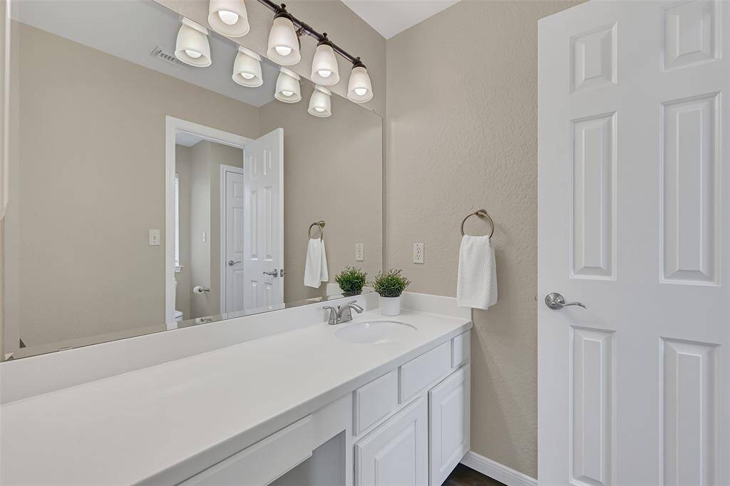 Jack & Jill bathroom designed for functionality and privacy, offering dual vanities with sleek white cabinetry and updated lighting, along with a central bathing area that includes a tiled tub/shower combo and private water closet access from each side.