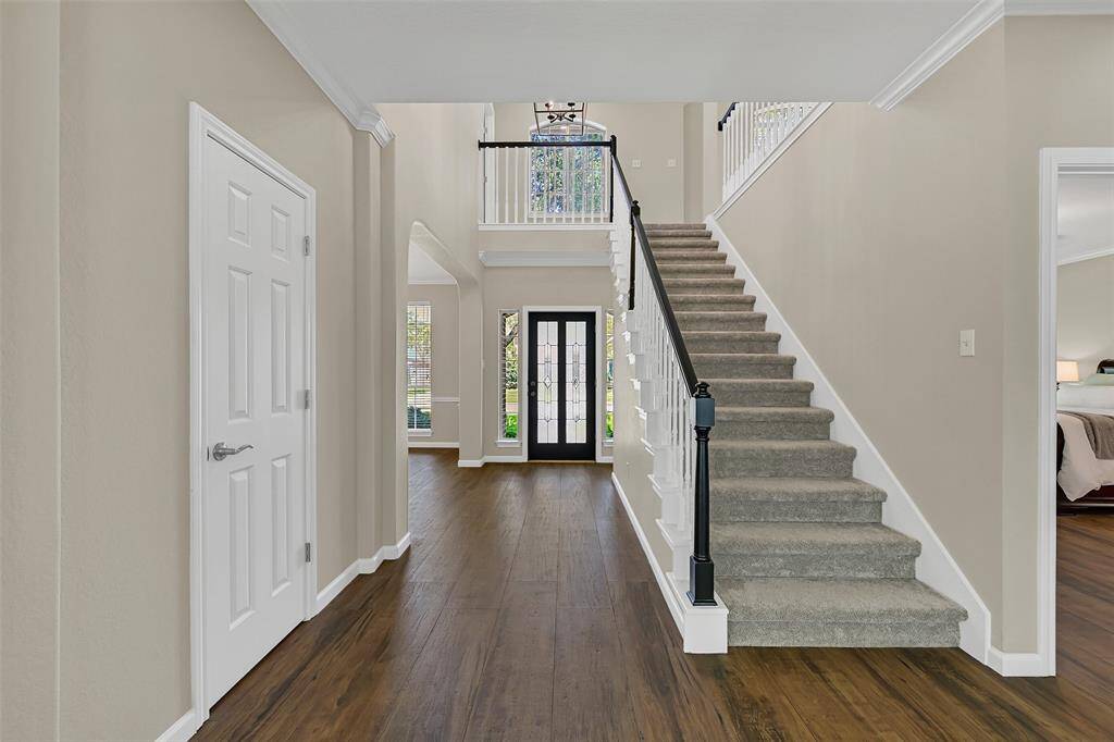 Step through the wood and leaded glass front door into this impressive two-story foyer that showcases soaring 18’ ceilings, rich wood-look tile floors, fresh neutral paint, and a statement light fixture that elevates the space.
