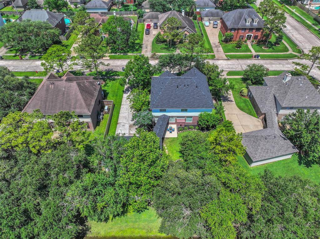 An aerial view of the property showcases the lush backyard with no rear neighbors and a brand new roof installed in 2025.