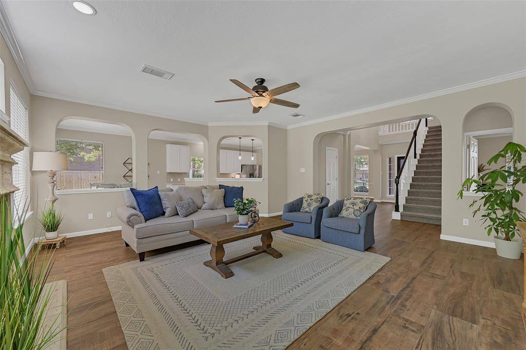 Continue straight ahead from the foyer into this spacious & inviting family room with fresh neutral paint, rxtra wide plank wood-look tile floors, crown molding, and graceful arched openings that flow into the kitchen and breakfast room.
