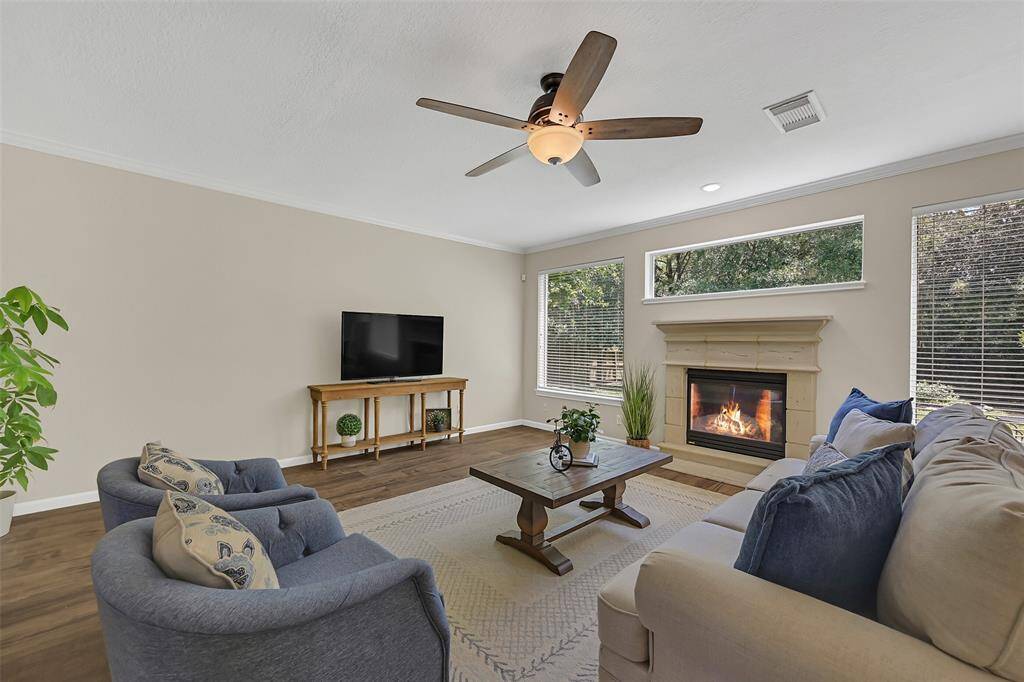 Cozy up by the cast stone gas fireplace in this inviting living room, filled with natural light from a wall of windows surrounding the fireplace and overlooking the backyard.