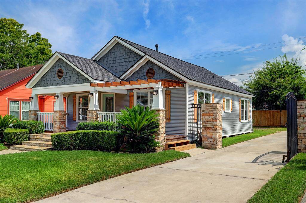 TASTEFUL LANDSCAPING ADORNS THE FRONT YARD AND THE DRIVEWAY FEATURES AN IRON GATE.