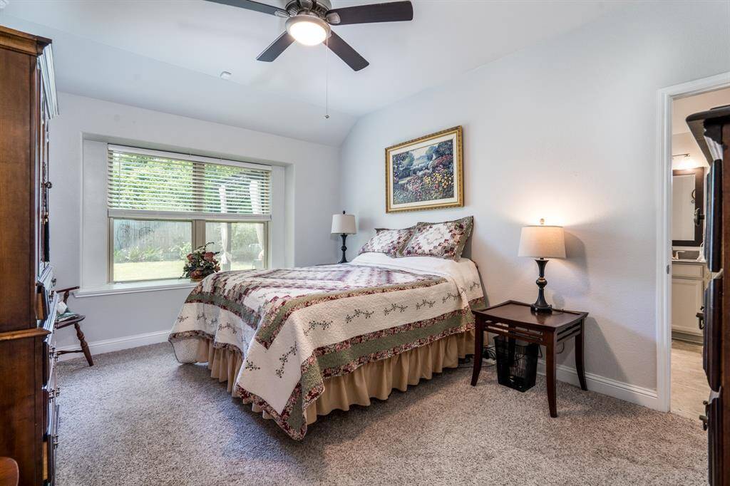 The primary bedroom features a stunning wall of windows, complete with a window seal, allowing natural light to flood the space while adding a charming architectural detail. The lush carpeting enhances the warmth and comfort of the room.