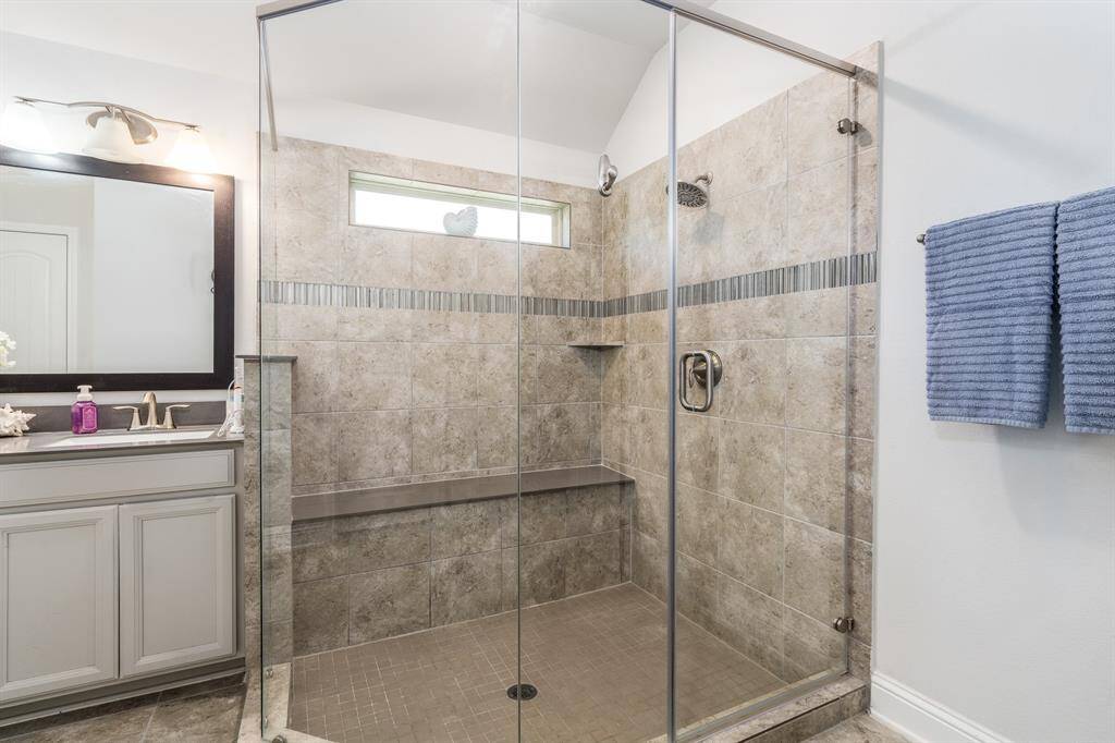 The primary bath boasts an oversized shower, offering a spa-like experience with plenty of space and modern finishes.