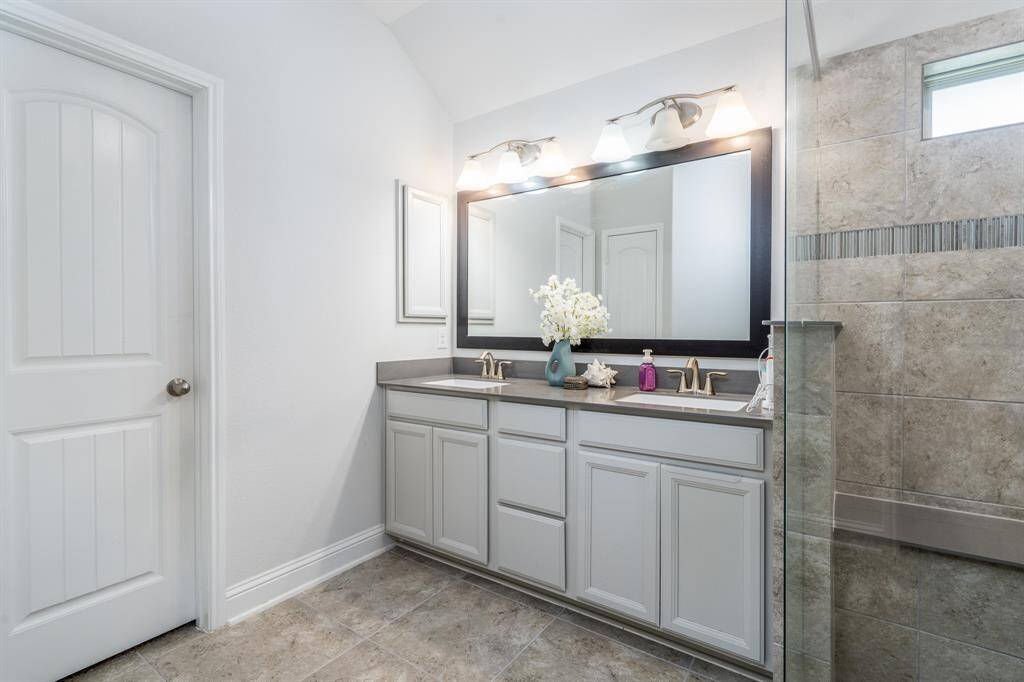 The primary bath features ample counter space with dual sinks, providing plenty of room for daily routines. Abundant lighting highlights the space, creating a bright and inviting atmosphere.