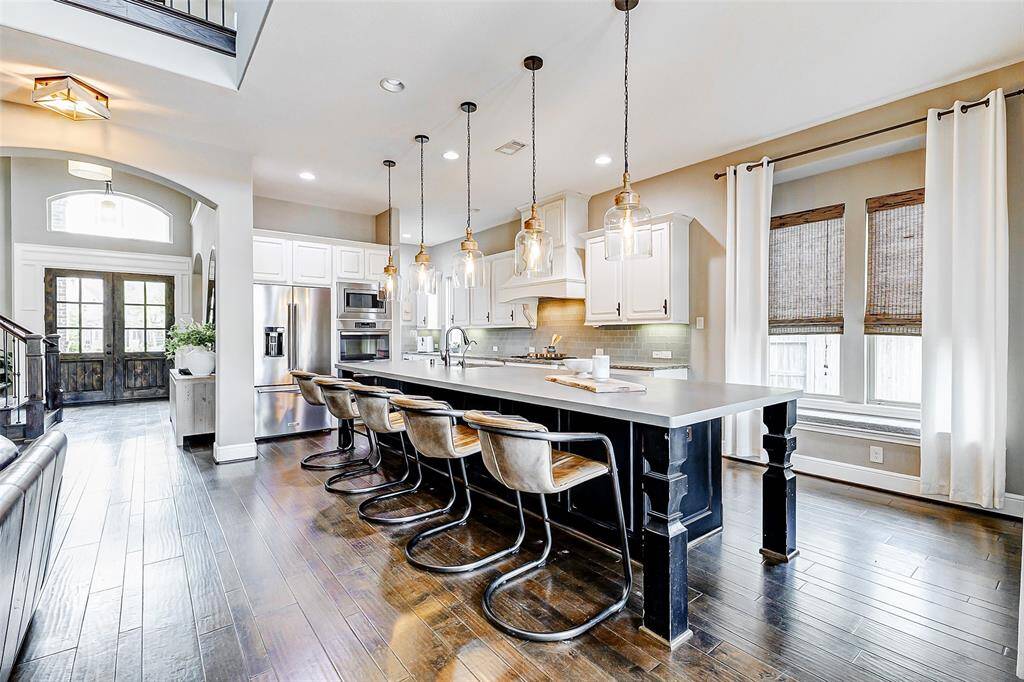 The generous breakfast bar offers additional seating, making it the ideal spot for a casual meal. Five striking pendant lights, with their unique shape and elegant finish, beautifully complement the kitchen's stylish design, adding a touch of sophistication.