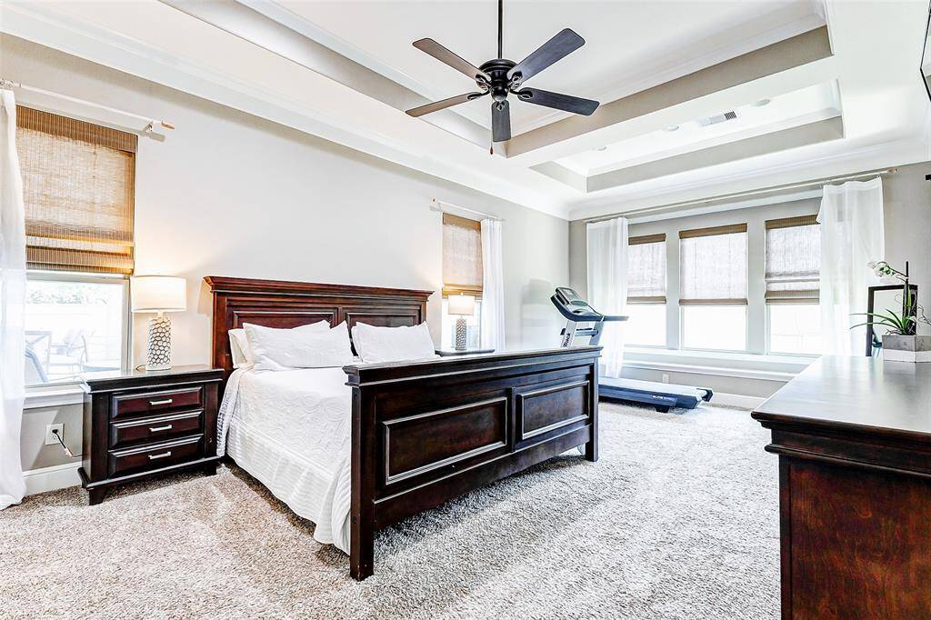 The spacious primary bedroom features elegant tray ceiling insets and a cozy sitting area by the wall of windows, offering the perfect retreat.