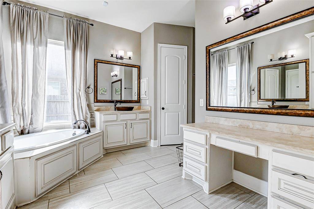 Vanity number three includes a convenient sitting area, ideal for preparing for the day ahead. Abundant drawers provide ample storage for toiletries, while the framed mirror and matching lighting fixture seamlessly complement the other vanities, creating a cohesive and functional space.