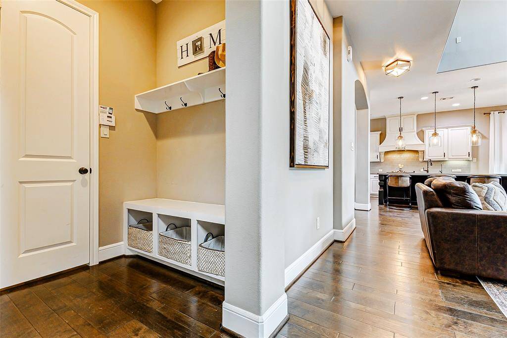 This functional mudroom features a built-in bench seat with three convenient cubbies for storage, along with a shelf and hooks ideal for hanging backpacks and coats. Just beyond, access to the epoxied four-car tandem garage provides seamless transition and ample space for all your needs.
