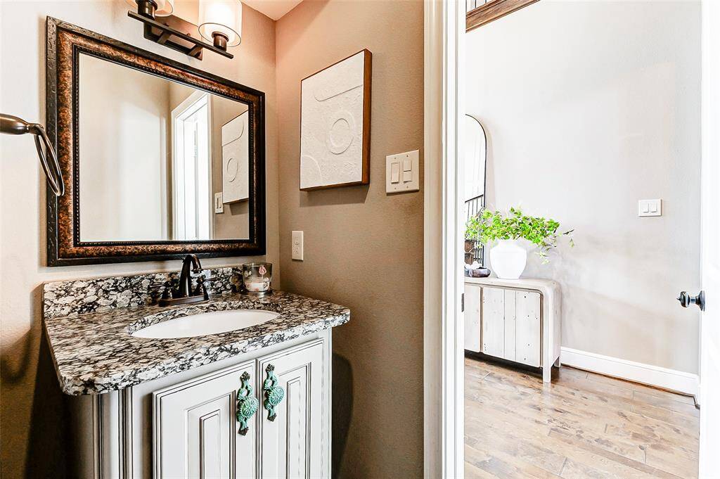 The downstairs powder bathroom located near the entry features a vanity with built-in storage, a framed mirror, and an upgraded lighting fixture.