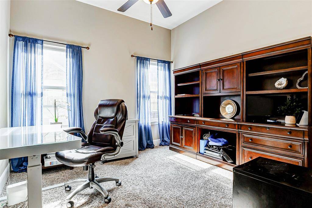 The secondary bedroom downstairs, currently utilized as an office, boasts decorator paint, plush carpeting, a ceiling fan, and two large windows that flood the room with natural light. For added convenience, it includes its own ensuite bathroom.