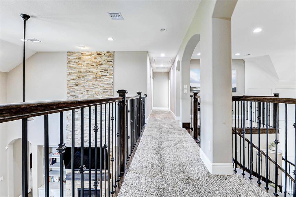 Ascend the elegant wooden staircase to discover the upstairs catwalk, along with the spacious secondary bedrooms, game room, and a dedicated media room!