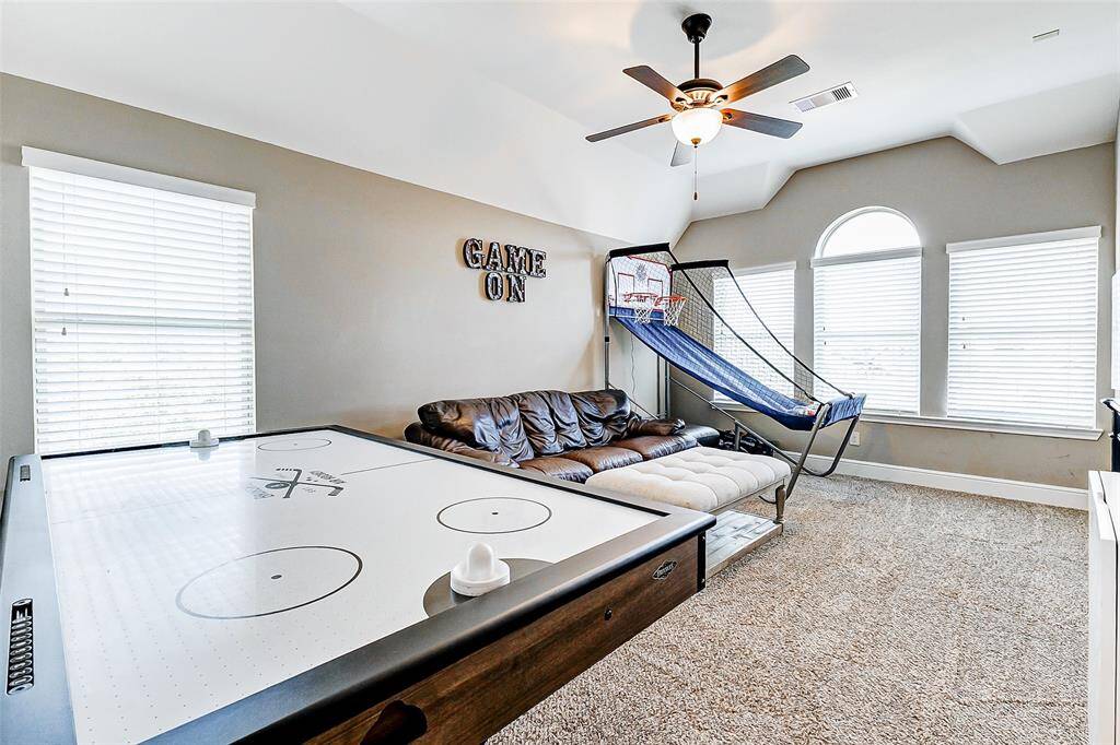 This spectacular game room is flooded with natural light, thanks to an abundance of windows, and features high ceilings that amplify the airy atmosphere. A ceiling fan enhances both the room’s ambiance and air circulation, making it the perfect space for a playroom, entertainment hub, or casual lounge.