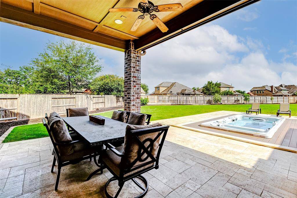 The expansive covered patio showcases elegant travertine decking, perfect for outdoor entertaining year-round. Just beyond, a vaulted MasterSpa swim spa—set on durable Trex decking and added in 2024—offers the ultimate in relaxation and wellness.