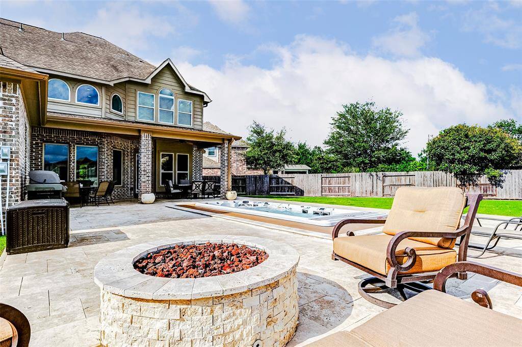 The travertine decking seamlessly extends to a beautifully crafted stone firepit, added in 2023—an ideal setting for cozy evenings spent with friends and family under the stars.