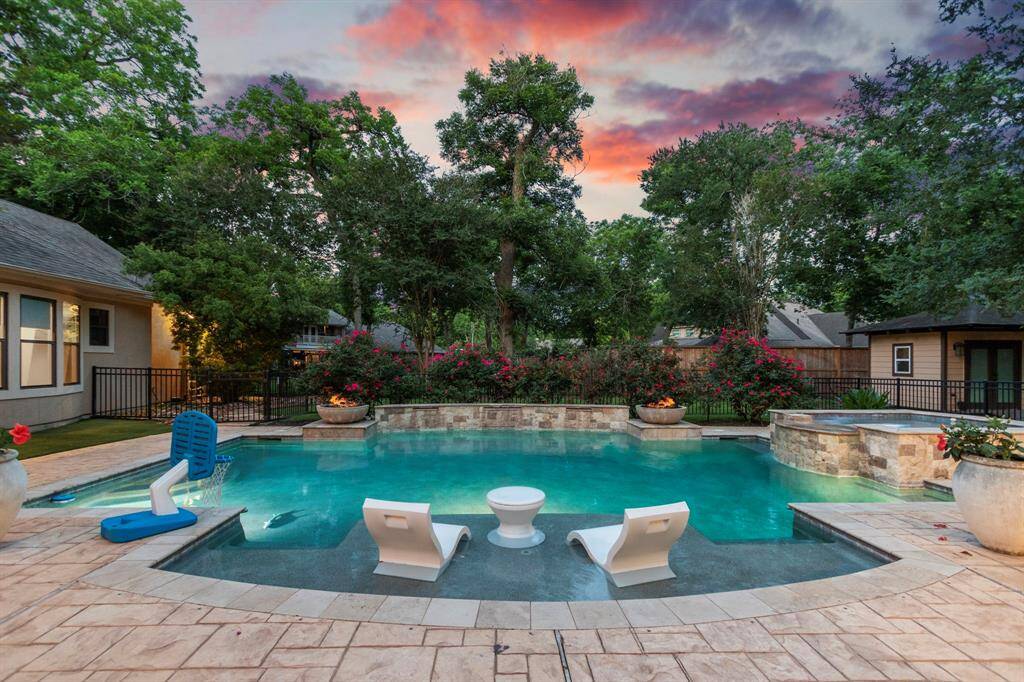 A beautiful backyard with pool, covered patio and outdoor kitchen. The pool features in-water loungers, perfect for relaxation.