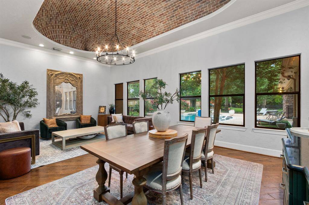 Dining/living area features the craftmanship of barrel-vaulted brick ceiling, natural light floods in through multiple windows, offering views of the pool and outdoor space.