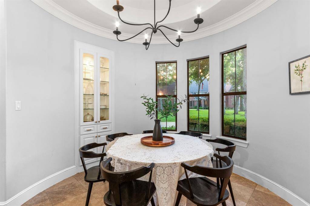Breakfast nook features large windows offering a view of the outdoors, a simply stylish chandelier.