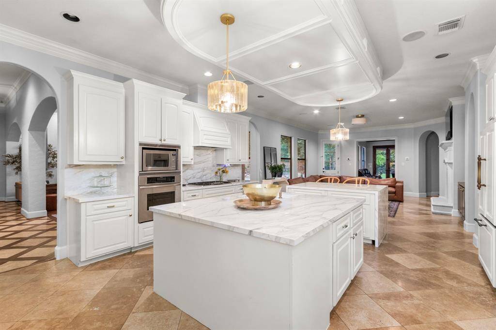 Elegant white cabinetry, modern stainless steel appliances, and a large porcelain-topped island.