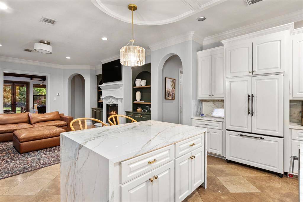 Spacious and elegant kitchen with a porcelain island and white cabinetry, open to family areas.