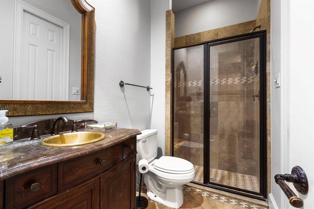 Secondary stylish bathroom with classic wood vanity with a marble countertop, and a gold-toned sink.