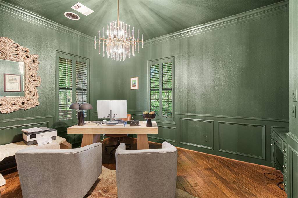 Gorgeous home office features a contemporary chandelier, and hardwood floors. A warm and sophisticated workspace.