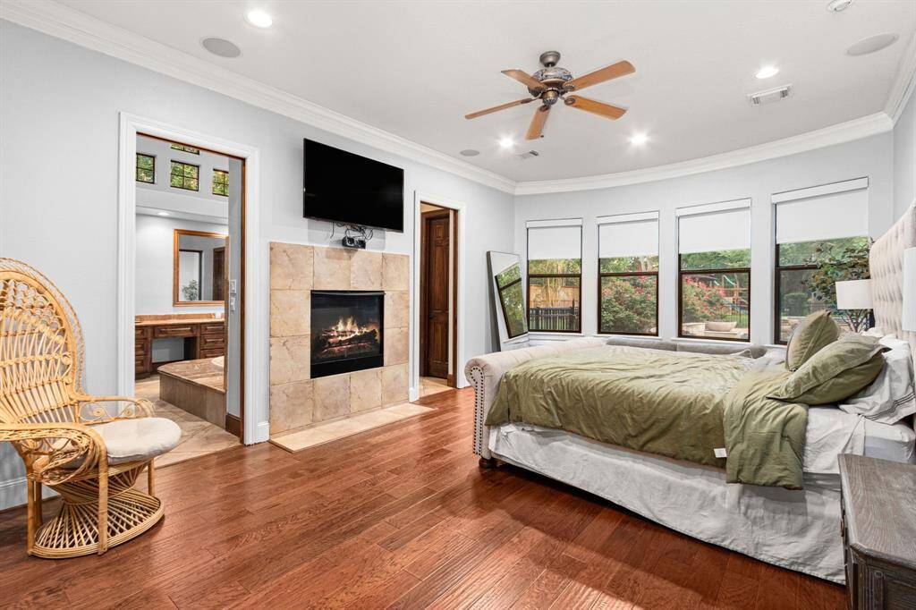 The spacious primary bedroom features hardwood floors, a cozy fireplace, and large windows offering ample natural light.