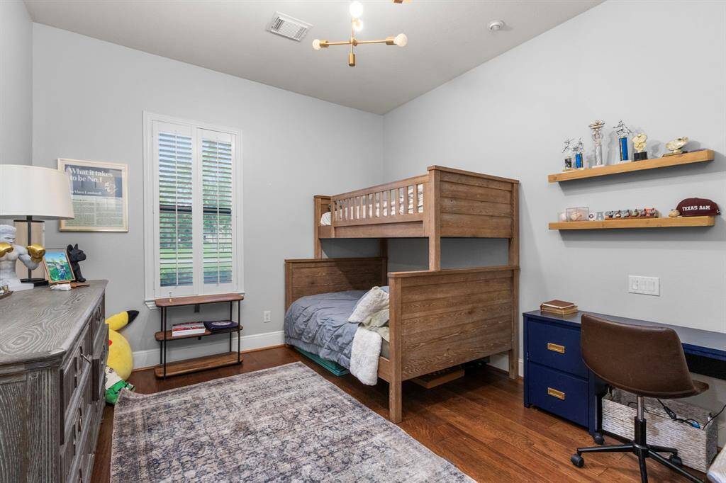 This cozy bedroom features, hardwood floors, and a large window with shutters. Perfect for a child's room or guest space.